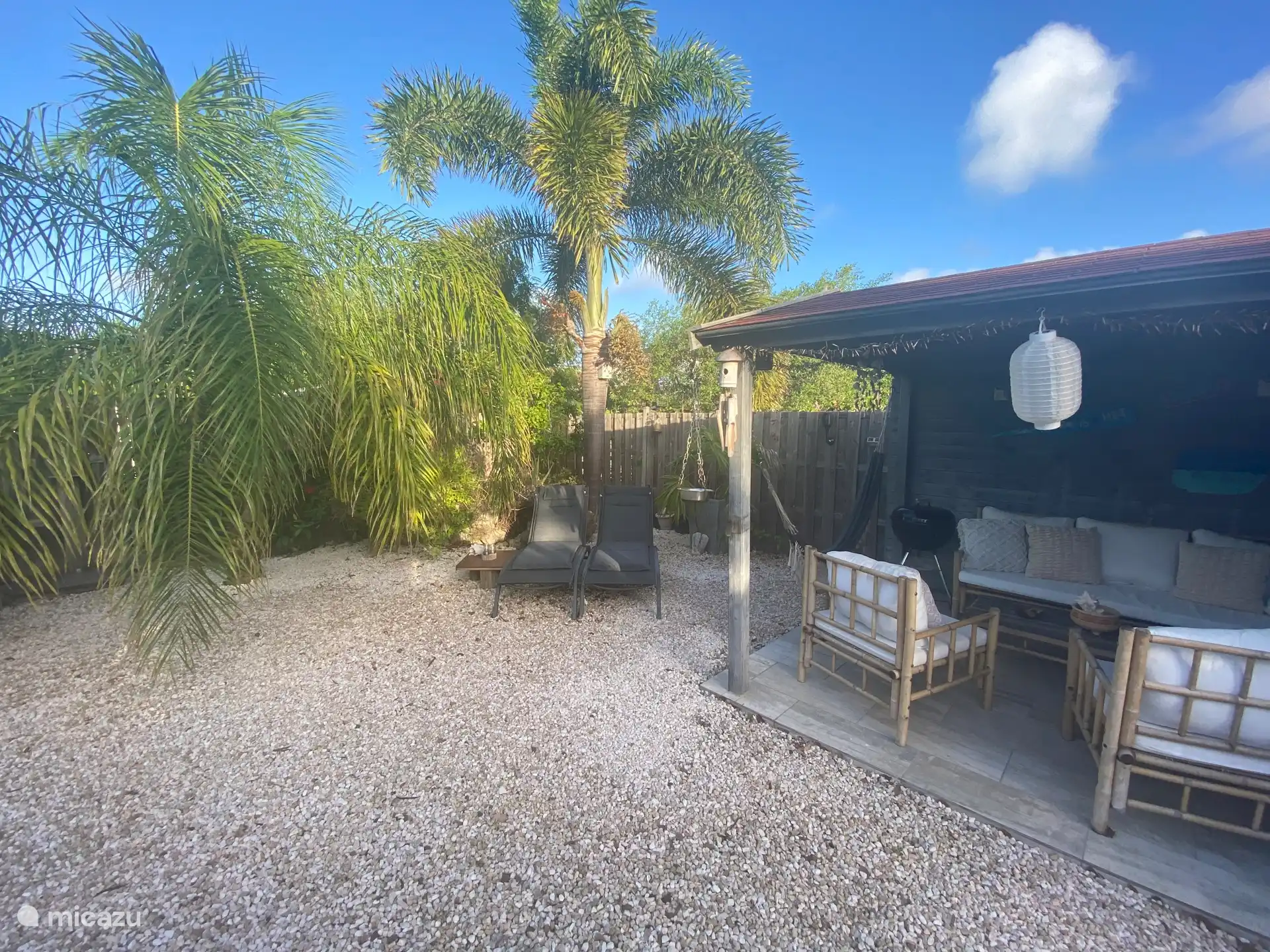 Covered seating area and sunbeds at the back of the tropical garden
