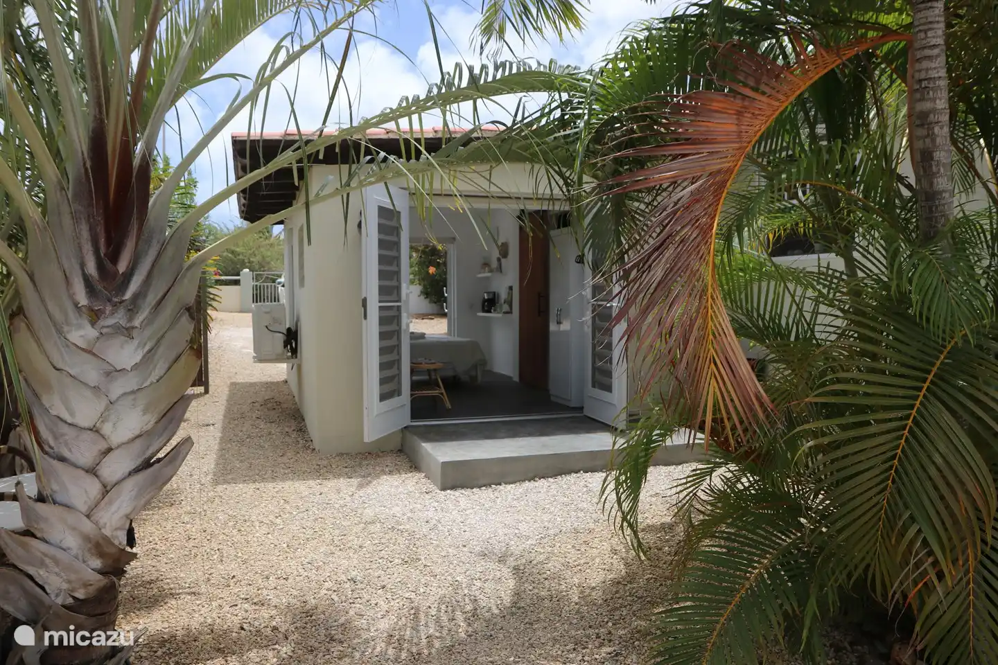 The garden room (3rd room) with shower, toilet and sink seen through the palms