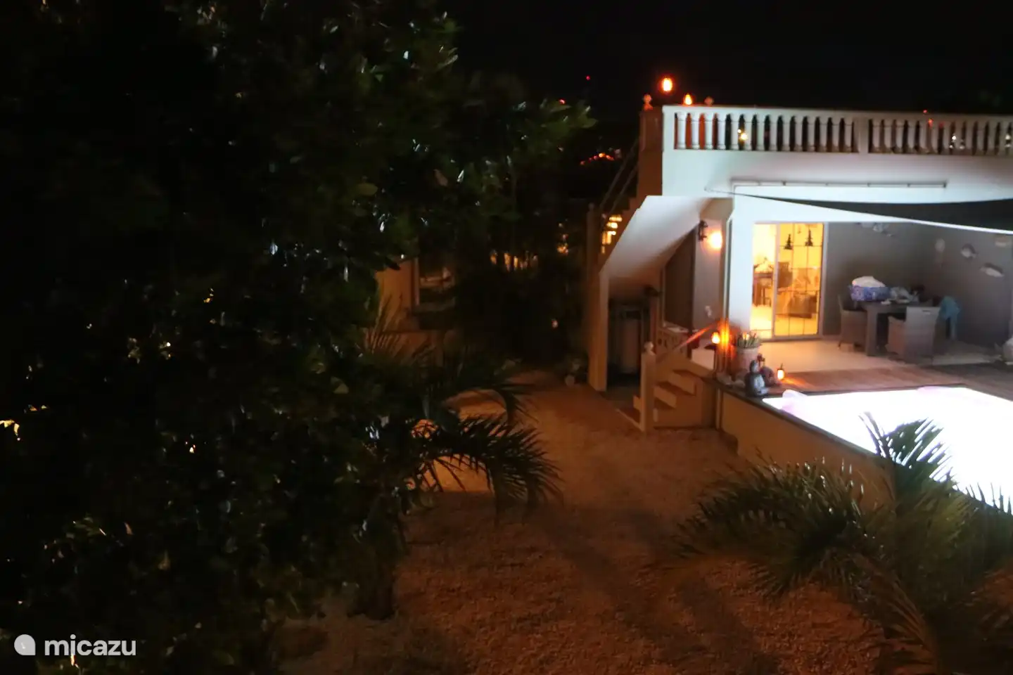 View of the back of the house with roof terrace, pool and various seating areas in warm light