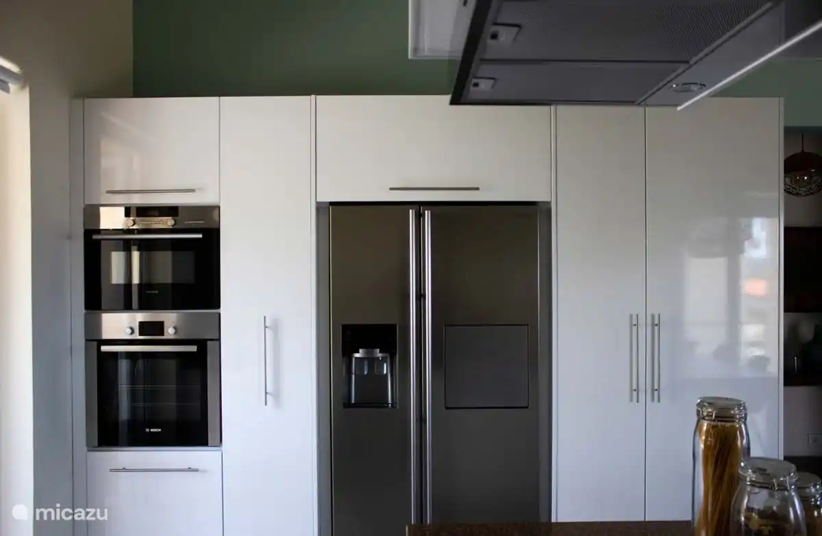 Una cocina totalmente equipada con mucho espacio de almacenamiento, frigorífico americano, horno, microondas, placa de inducción con campana extractora y lavavajillas.