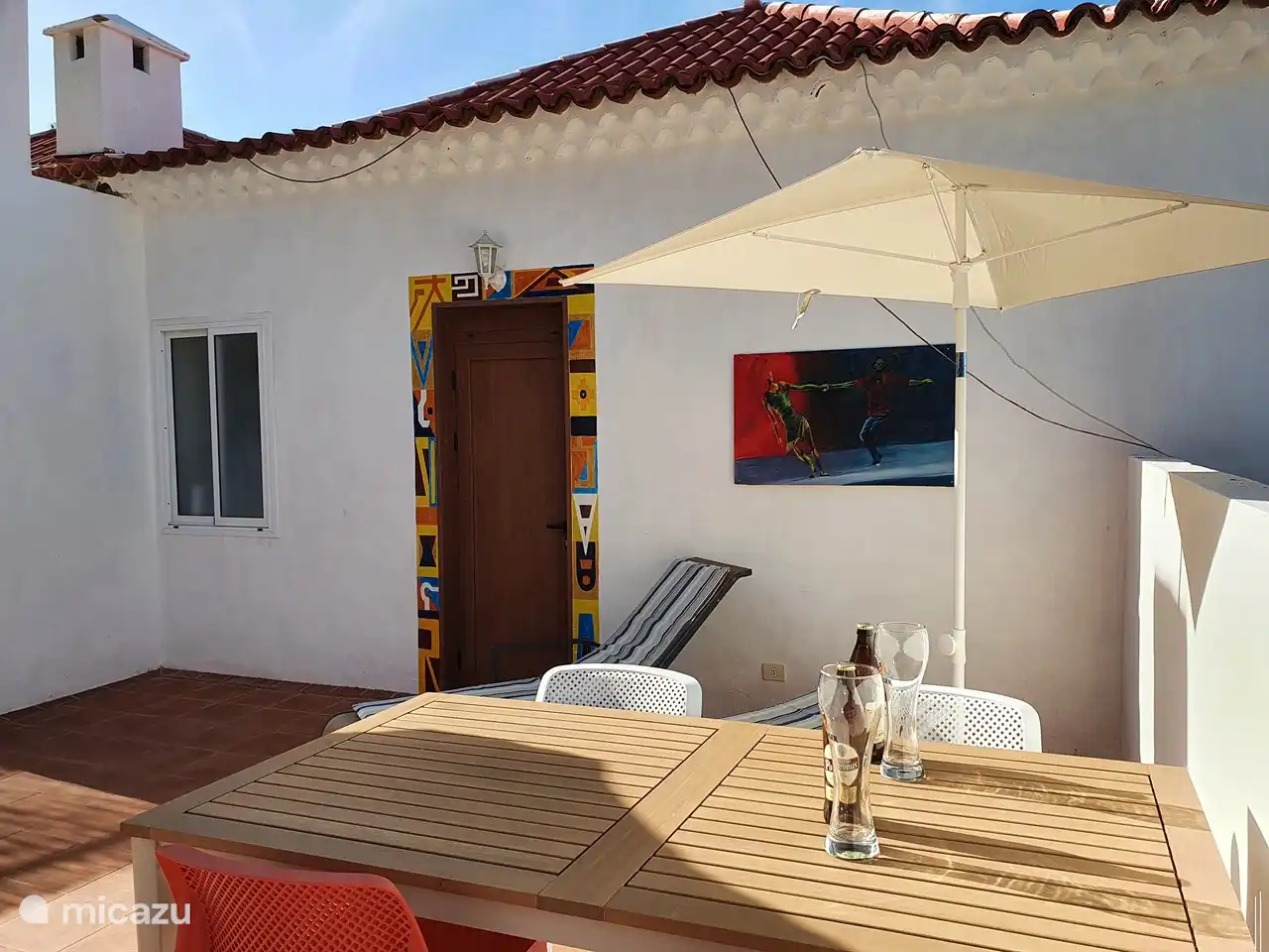 Parte delantera de la terraza con camas tipo lug, zona de estar y dormitorio con barra