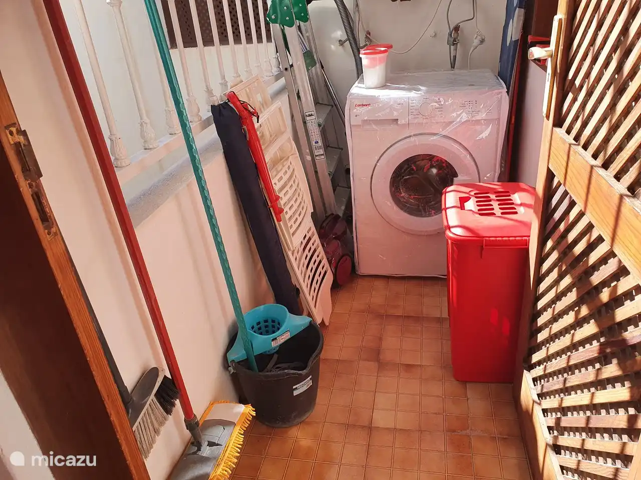 Lavandería con lavadora, tabla de planchar,
Sombrillas de playa con paraguas, cubo, escoba y fregona