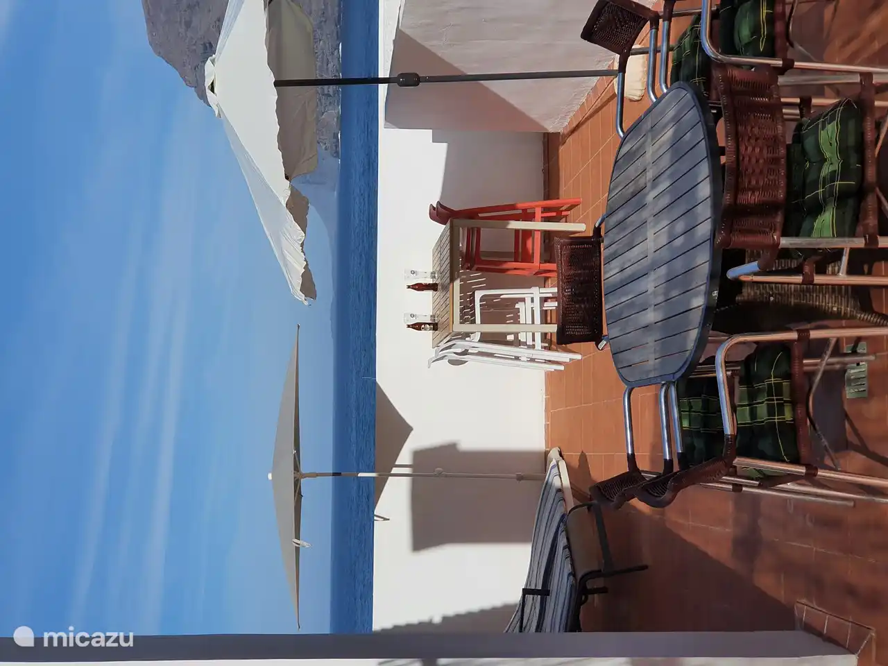Nuestra enorme terraza con una mesa alta con 4 taburetes de barra a este lado para que puedas contemplar el puerto, el océano y las rocas 