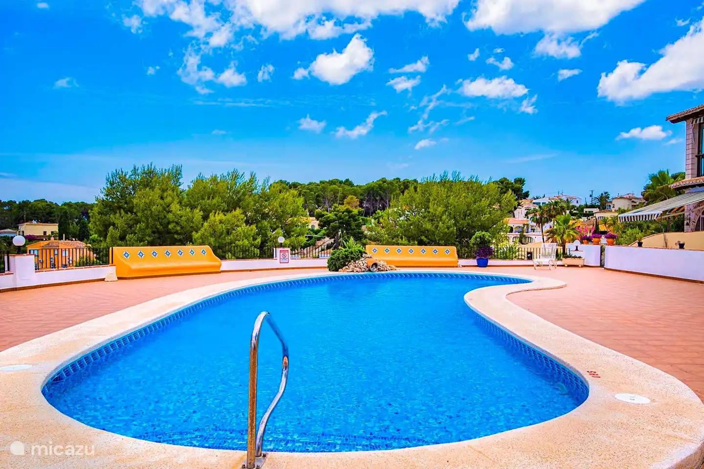 Gemeinschaftspool mit großzügiger Terrasse für Sonnenliegen.