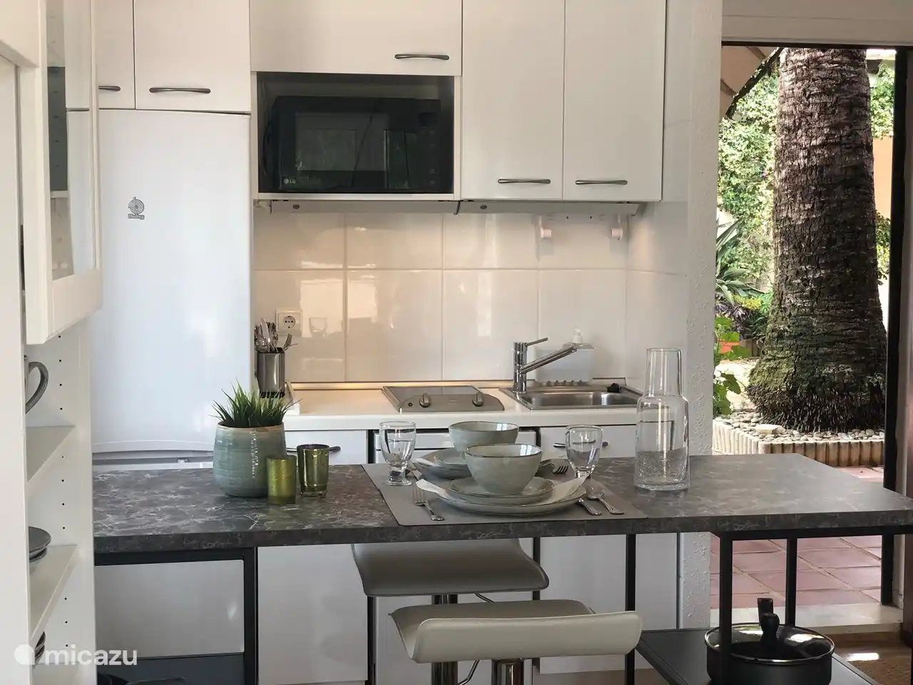 Wohnzimmer mit offener Küche, Geschirrspüler, Kühlschrank, Mikrogrill und Herd