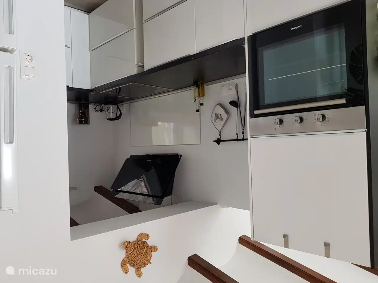 L-förmige Küche (Erdgeschoss) mit Backofen, Elektroherd, Dunstabzugshaube, Geschirrspüler, Mikrowelle, Kühlschrank mit Gefrierfach.