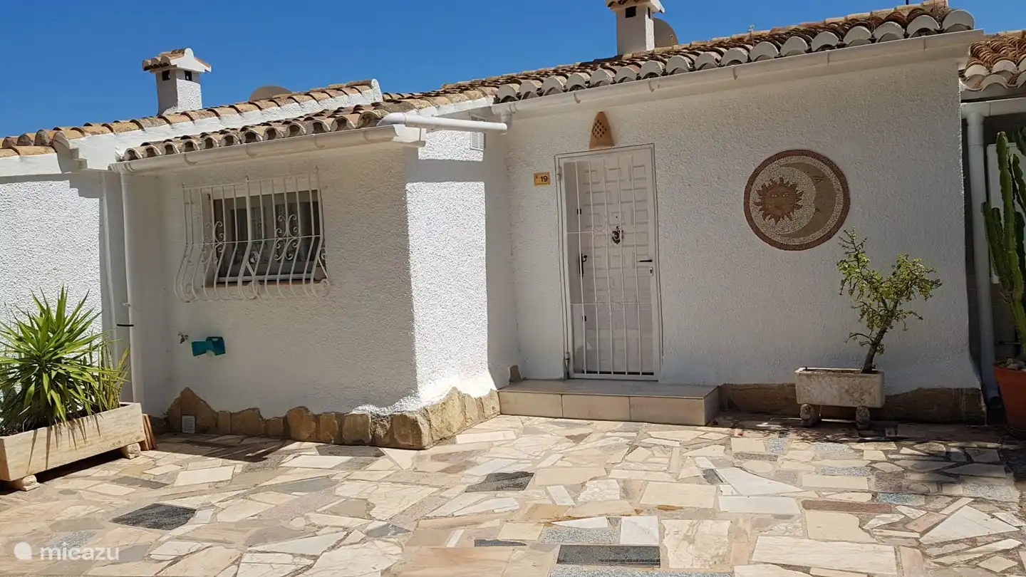 Fassade (Erdgeschoss) von La Trufa mit Küchenfenster, Haustür und Außenbeleuchtung. Parkplatz vor dem Haus.