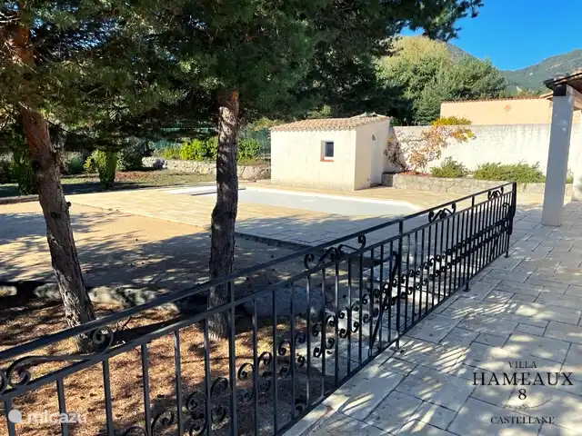 Vue sur le jardin avec terrain de pétanque et piscine.