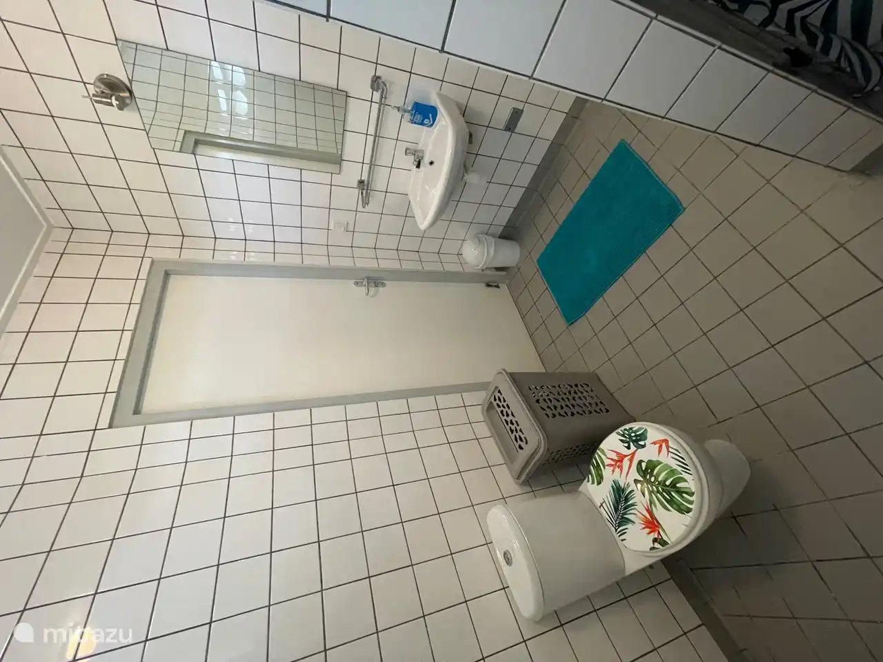 Salle de bain principale avec un panier à linge et des toilettes tropicales.