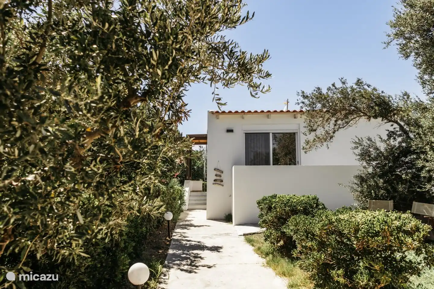 Der Eingang des Hauses, wo Sie das Auto unter den Bäumen parken können