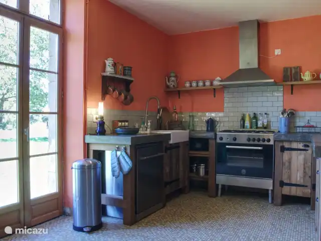 Casa de vacaciones Laume en Francia, Allier, Theneuille - casa vacacional La cocina con lavavajillas. También hay una lavadora y secadora en la cocina. El patio trasero es visible a través de la puerta.