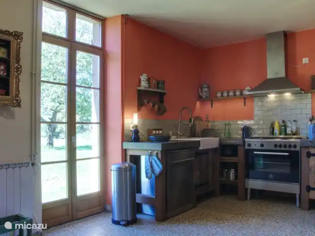 Casa de vacaciones Laume en Francia, Allier, Theneuille - casa vacacional La cocina con la puerta al patio trasero. La cocina también está decorada con elementos antiguos y antiguos en un enfoque moderno.
