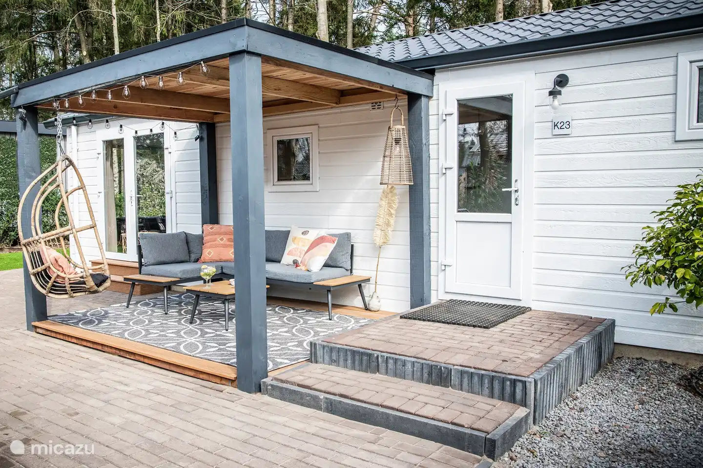 Was für eine schöne überdachte Terrasse mit diesem Loungesofa und diesem Hängesessel zum Entspannen!