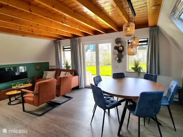 Ambiente y desmontaje en el parque de vacaciones en Países Bajos, Overijssel, Gramsbergen - casa vacacional La acogedora sala de estar, con una acogedora mesa de comedor redonda y las puertas del jardín a la terraza