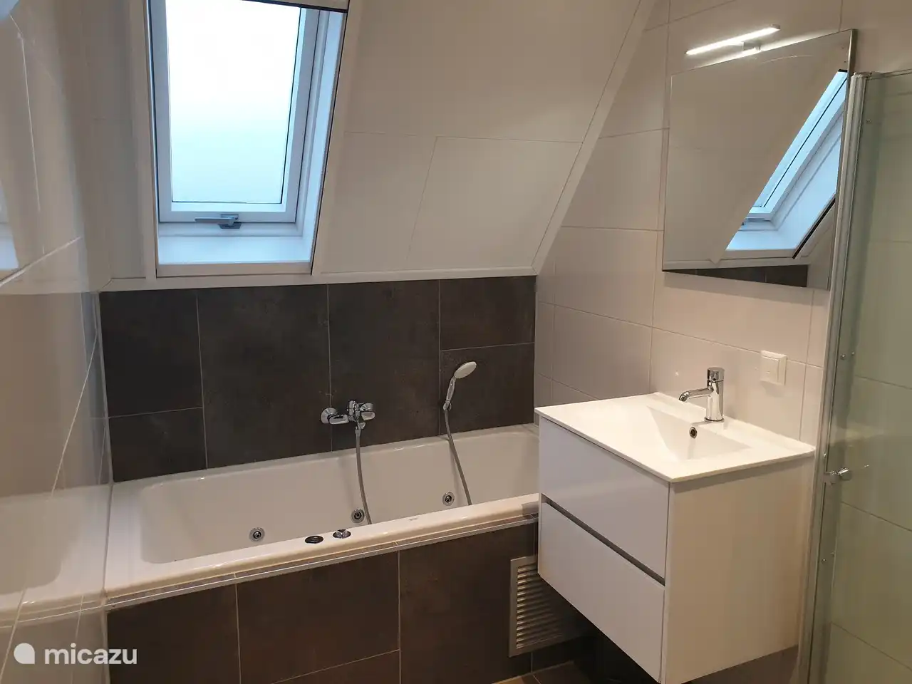 Cuarto de baño climatizado con ducha de efecto lluvia, bañera de hidromasaje y lavabo