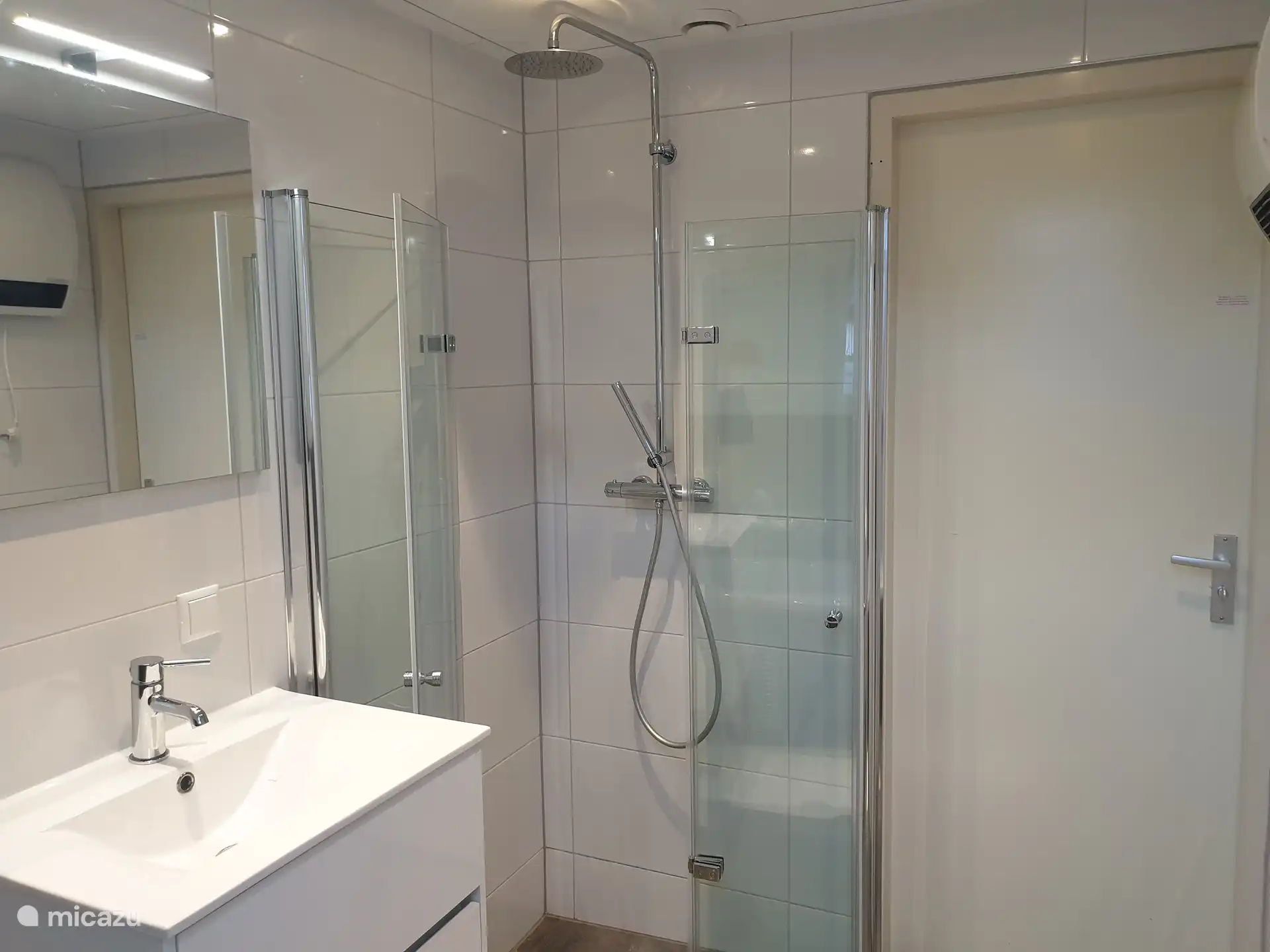 Cuarto de baño climatizado con ducha de efecto lluvia, bañera de hidromasaje y lavabo