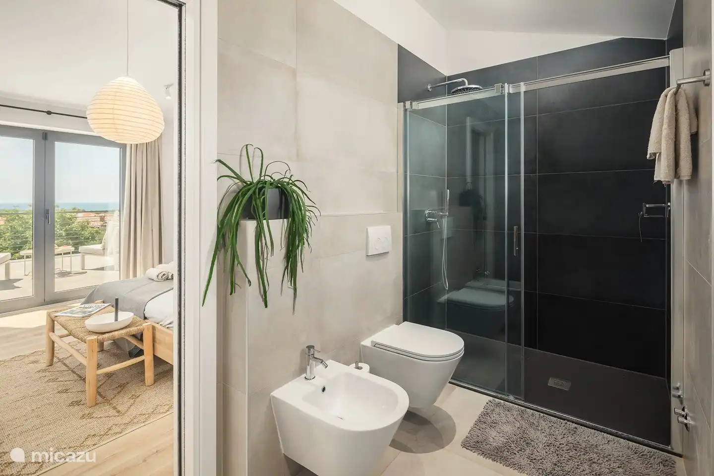 Badezimmer mit großzügiger ebenerdiger Dusche, WC, Bidet und Waschbecken.