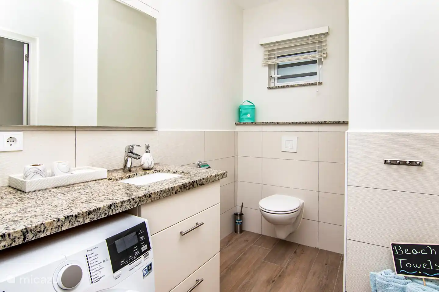 Bathroom with hanging toilet, washer-dryer combination.