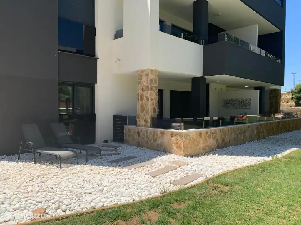 Terraza muy espaciosa con un encantador juego de salón, tumbonas y mesa de comedor con sillas