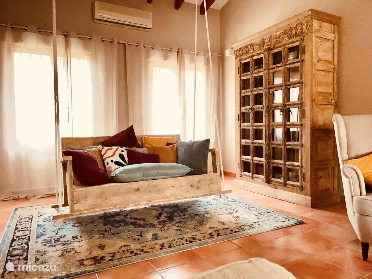 Schönes Schaukelsofa im Wohnzimmer neben dem antiken Bücherregal mit einer großen Auswahl an Büchern.