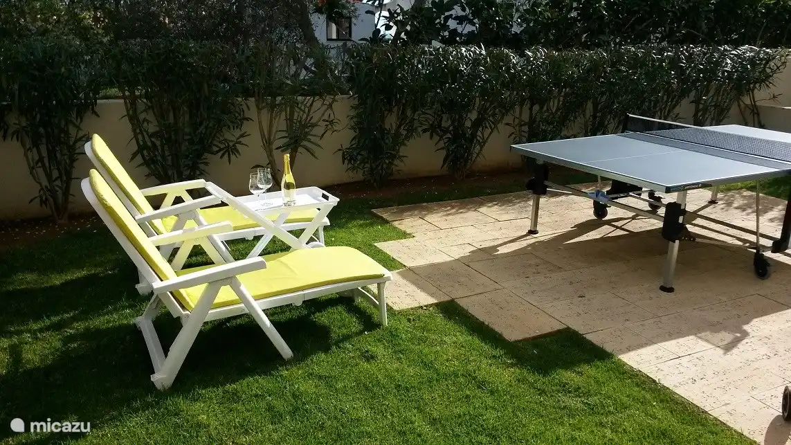 Eigen tuin met outdoor tafeltennistafel en lounge stoelen met serveerboy.
