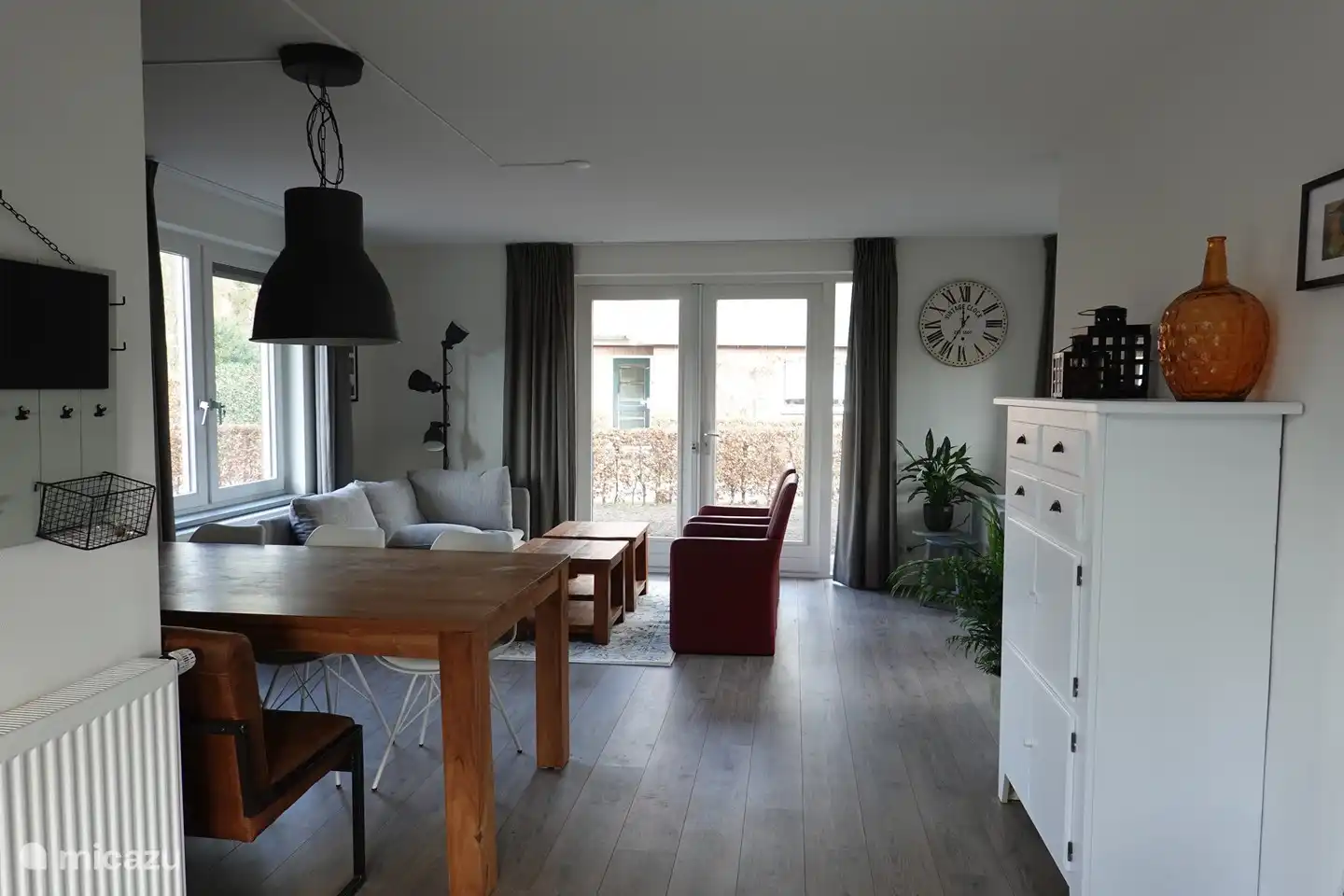 Le salon spacieux possède de nombreuses fenêtres et est très lumineux. a une vue sur le jardin qui entoure la maison