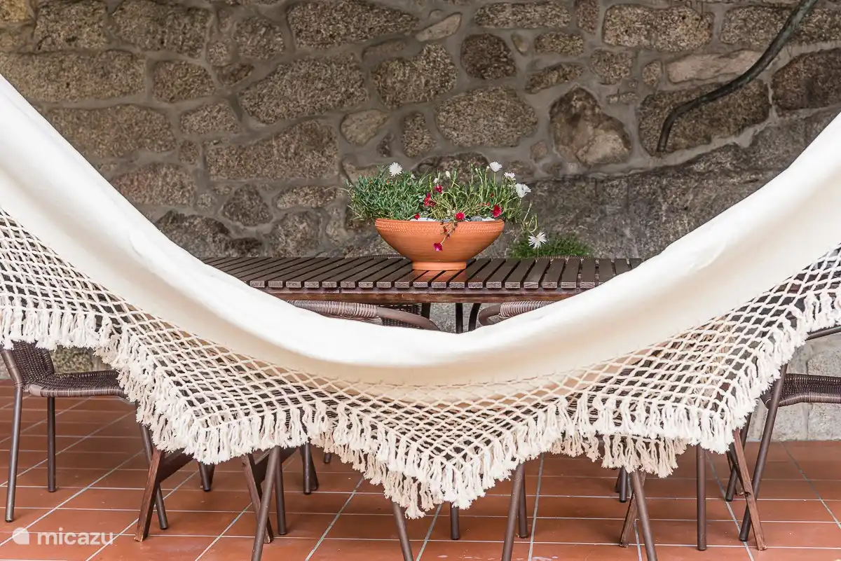 Überdachter, windgeschützter Innenhof mit Esstisch, Hängematte und Grill