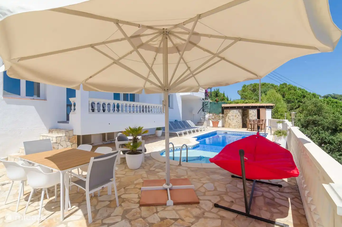 Auf der Rückseite sehen Sie das Steingebäude, in dem sich die Außendusche und die Toilette befinden