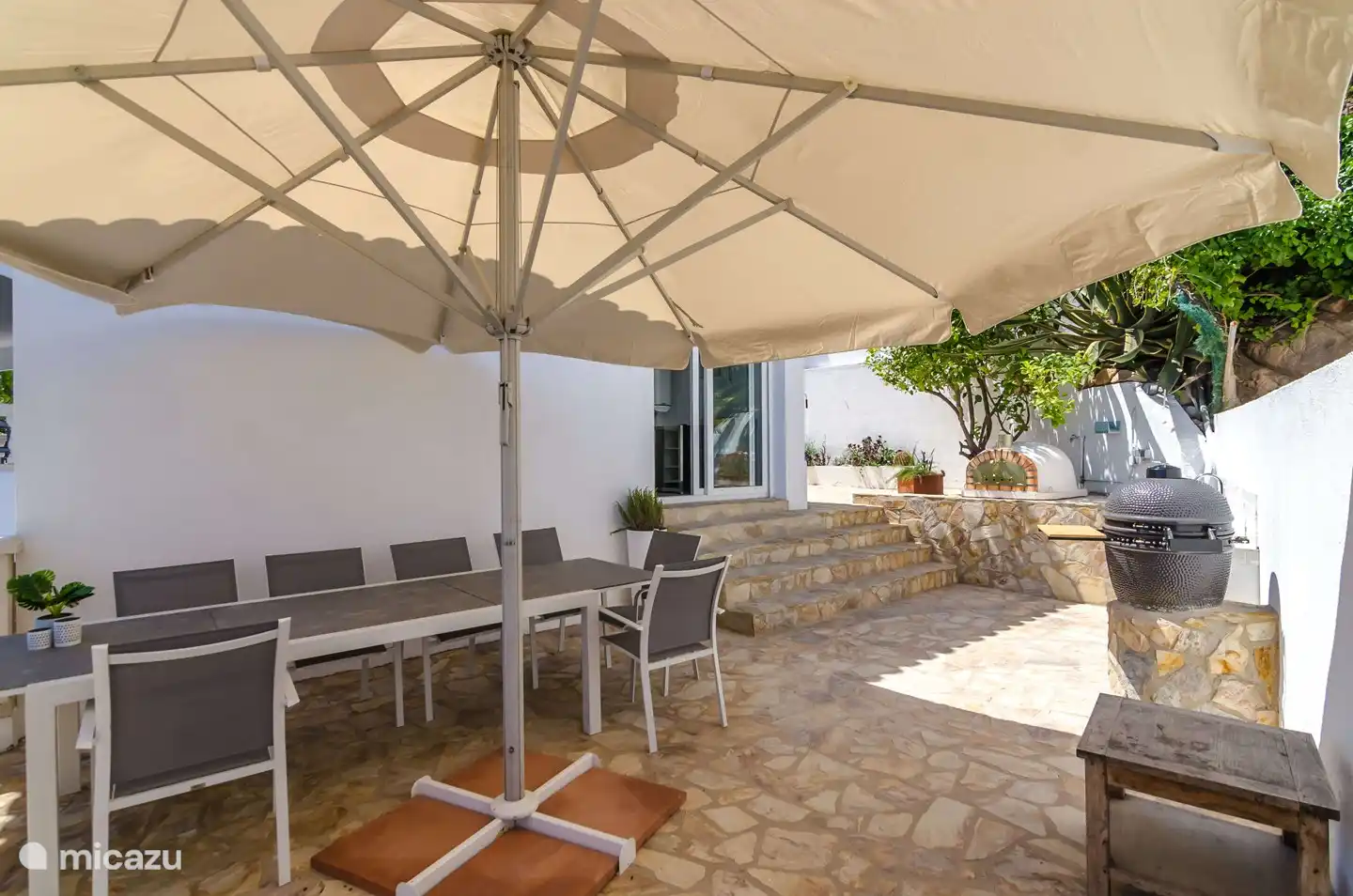 Terrasse mit großem Esstisch und Sonnenschirm