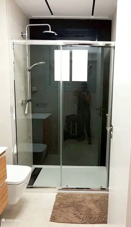 Badezimmer mit großzügiger Dusche, Waschbecken und Toilette, Fön ist ebenfalls vorhanden.