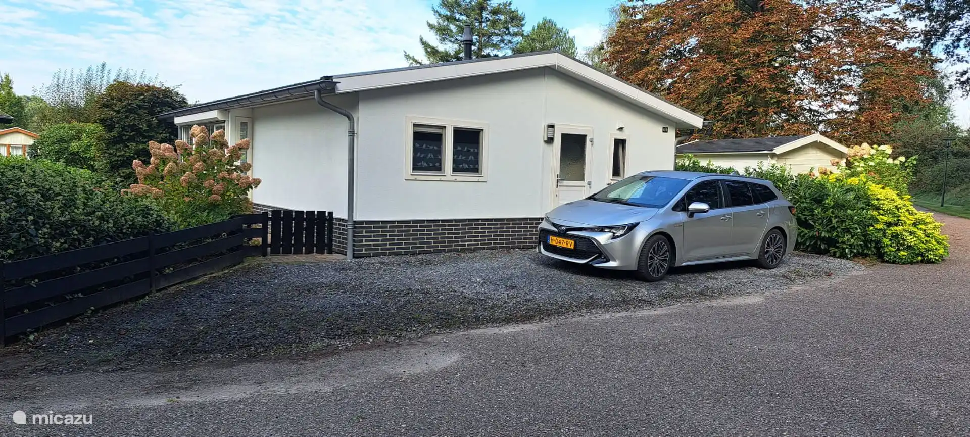 De voorkant van het chalet met parkeerplaats voor 2 auto's.