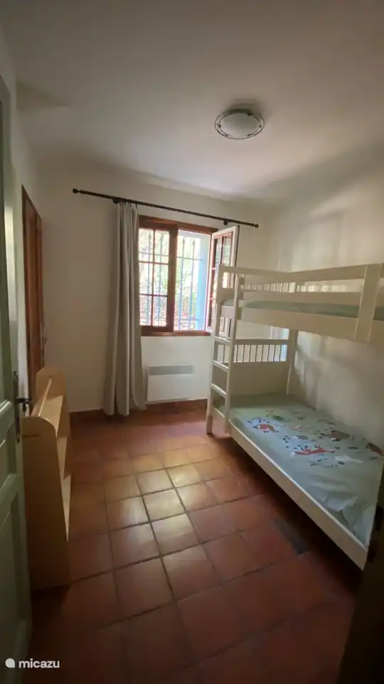 Ein cooles Schlafzimmer mit einem Etagenbett und einem Schrank mit Kinderspielzeug. 
Es steht ein Hochstuhl zur Verfügung.