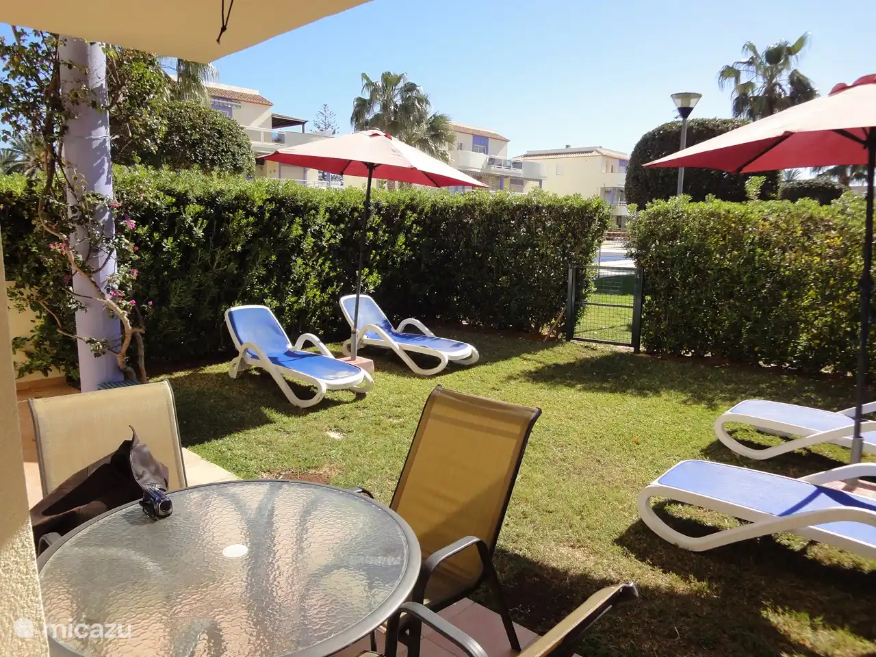 Der Garten mit Sonnenliegen und die Terrasse mit Tisch im Freien