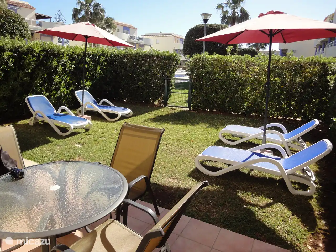 Der Garten mit Sonnenliegen und die Terrasse mit Tisch im Freien