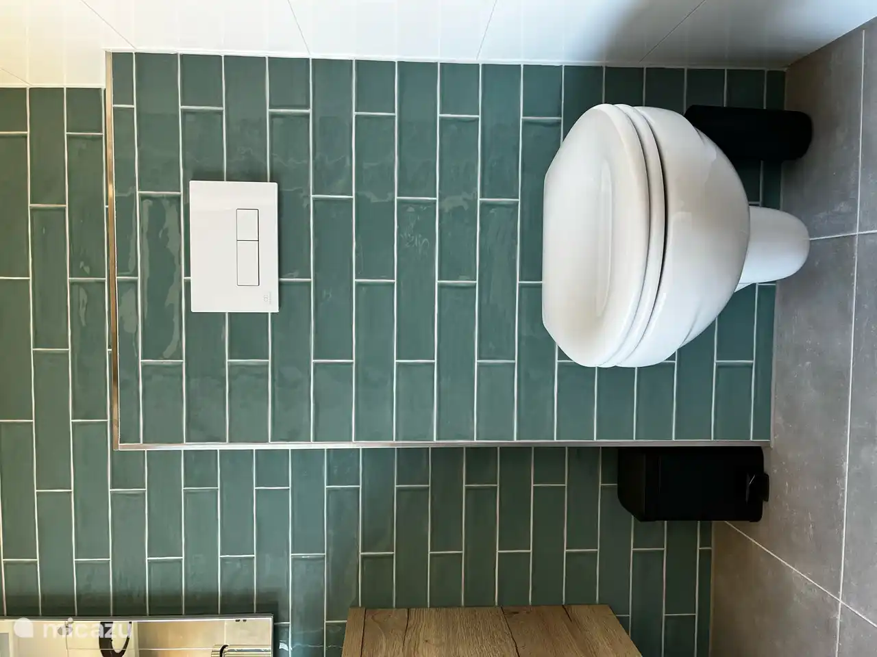 Das Badezimmer hat ein modernes Design mit jadefarbenen Fliesen auf einer Seite.