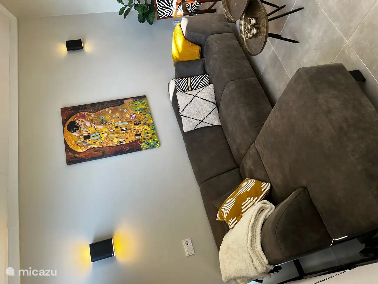 Ein helles Wohnzimmer, das gemütlich eingerichtet ist. Das Wohnzimmer wird mit Fußbodenheizung beheizt und verfügt über ein Ecksofa und zwei Sessel.