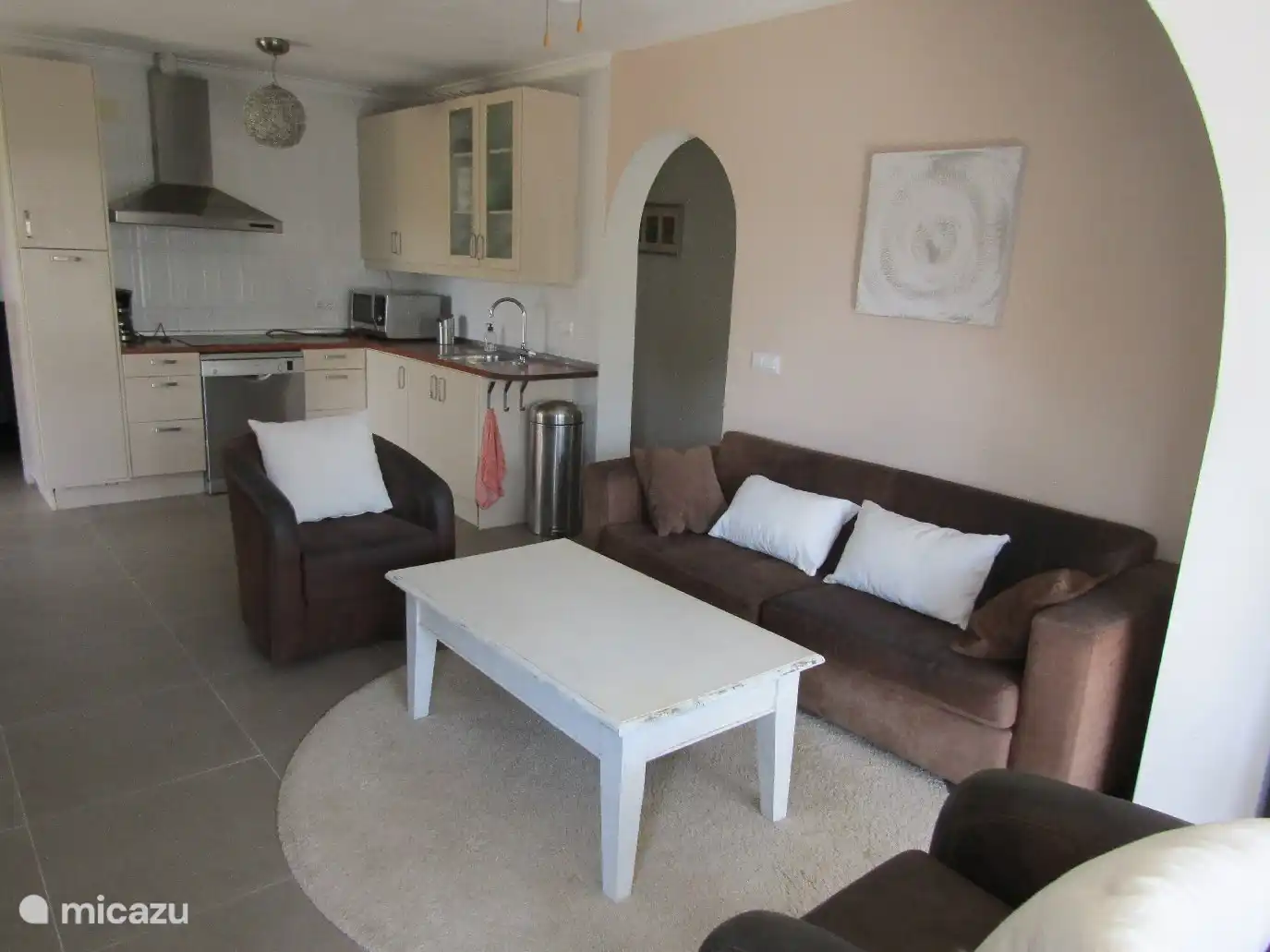 Séjour avec grand canapé et deux fauteuils. Dans la cuisine ouverte, vous trouverez tout ce dont vous avez besoin.