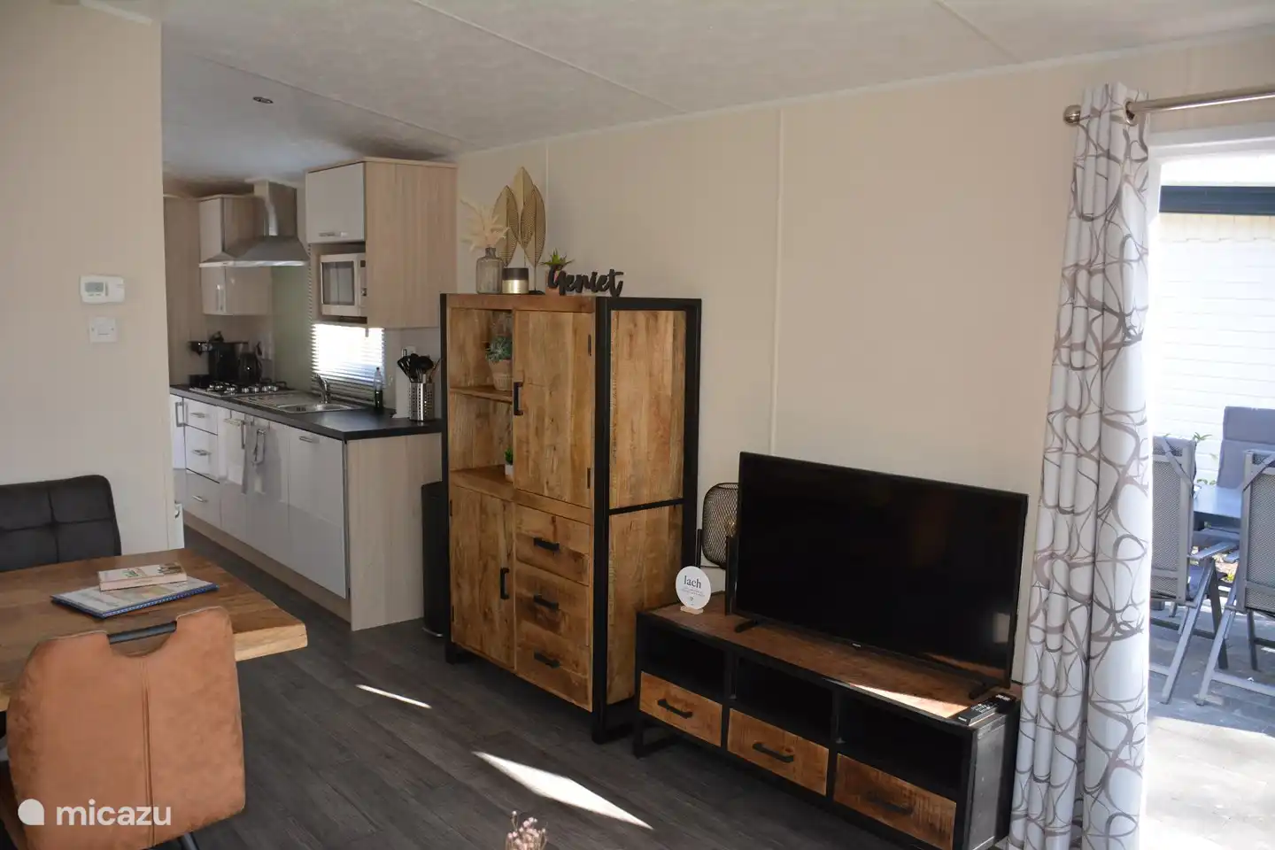 tv kast met 39 inch tv en een buffetkast gevuld met servies en ruimte om meegebrachte spullen in op te bergen. 