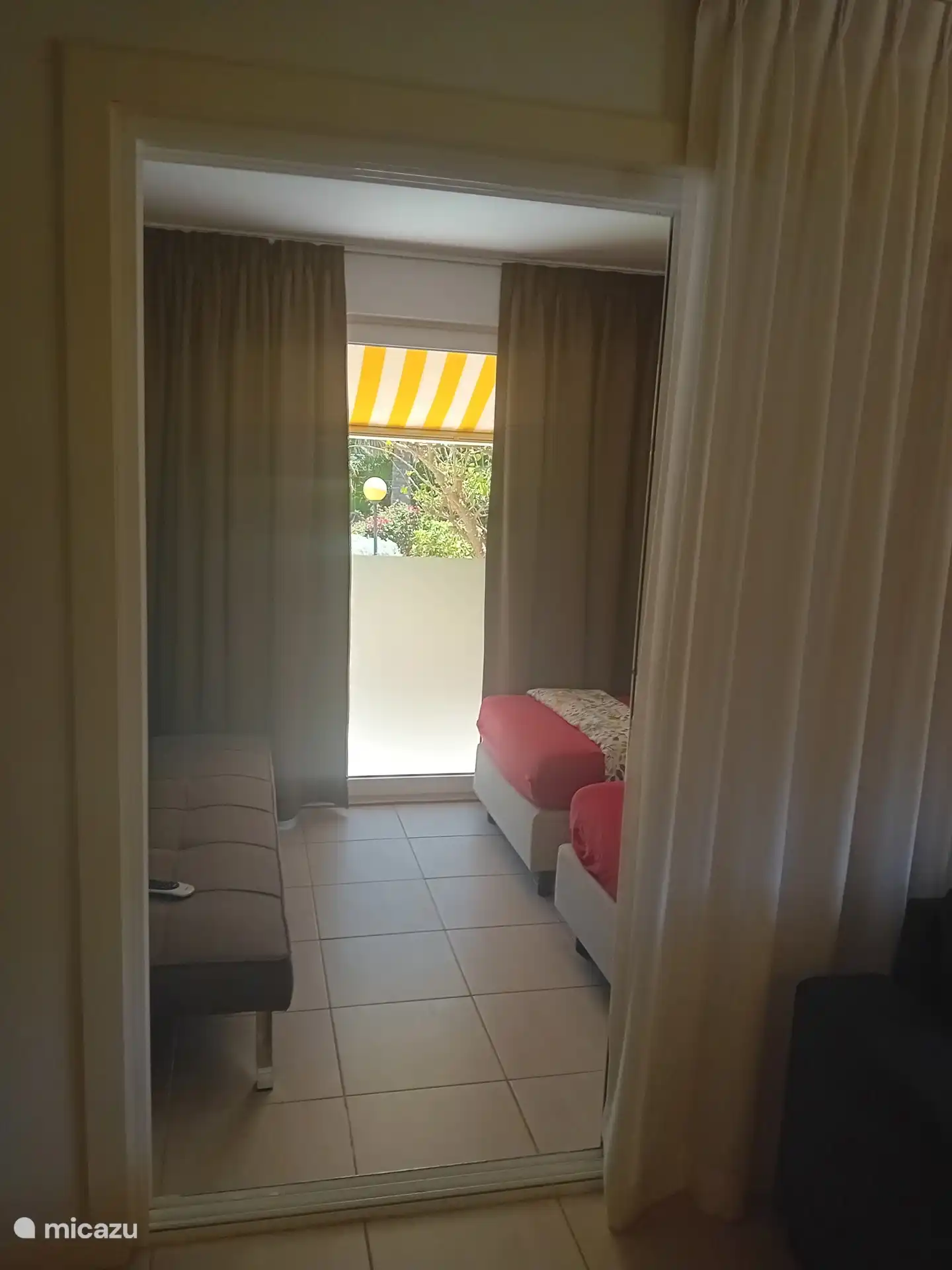Zweites Schlafzimmer mit Schlafsofa und Schiebetüren zum tropischen Garten. 