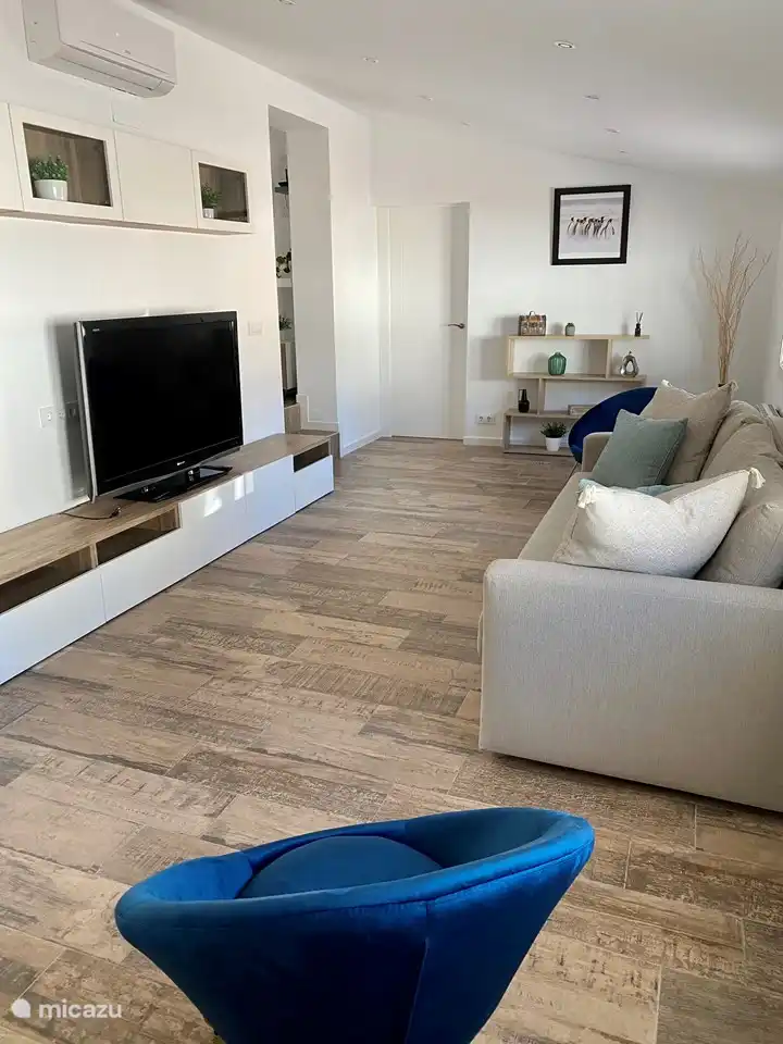 Geräumiges Wohnzimmer mit bequemem Sofa (kann in ein Zustellbett umgewandelt werden) und großem TV-Bildschirm.