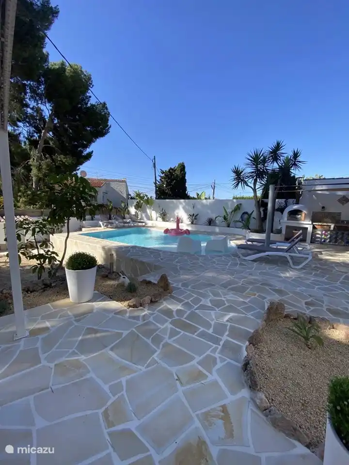 Der Pool und die Außenküche werden vom Esstisch gezeichnet.