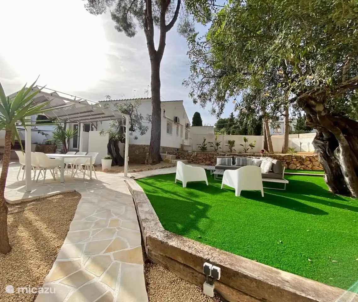 Überblick über den Garten mit Esstisch und Loungebereich. Das Schwimmbad ist auf der linken Seite.