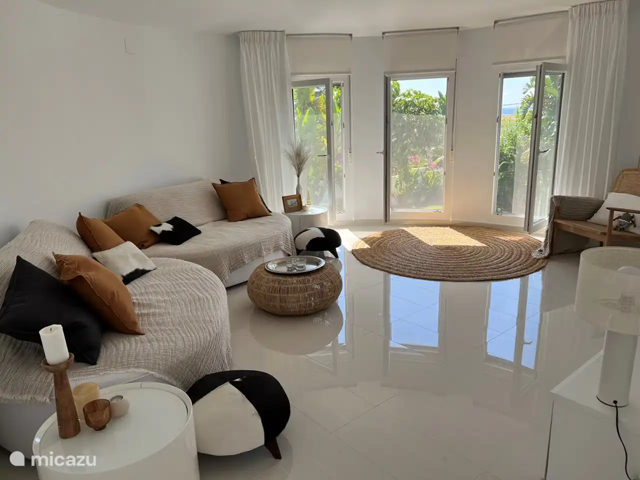 Woonkamer 1e etage met 3 openslaande ramen (incl sunscreens, horren en rolluiken)  met uitzicht op zwembad, tuin & zee