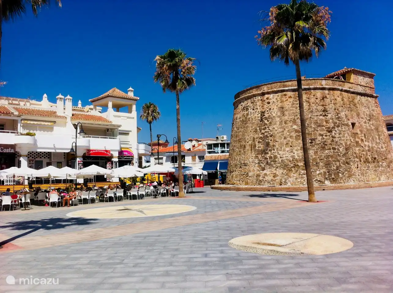 La acogedora plaza del pueblo en la playa como punto de encuentro. Aqu&#237; hay restaurantes, una helader&#237;a, un chiringuito, un trampol&#237;n y parques infantiles.