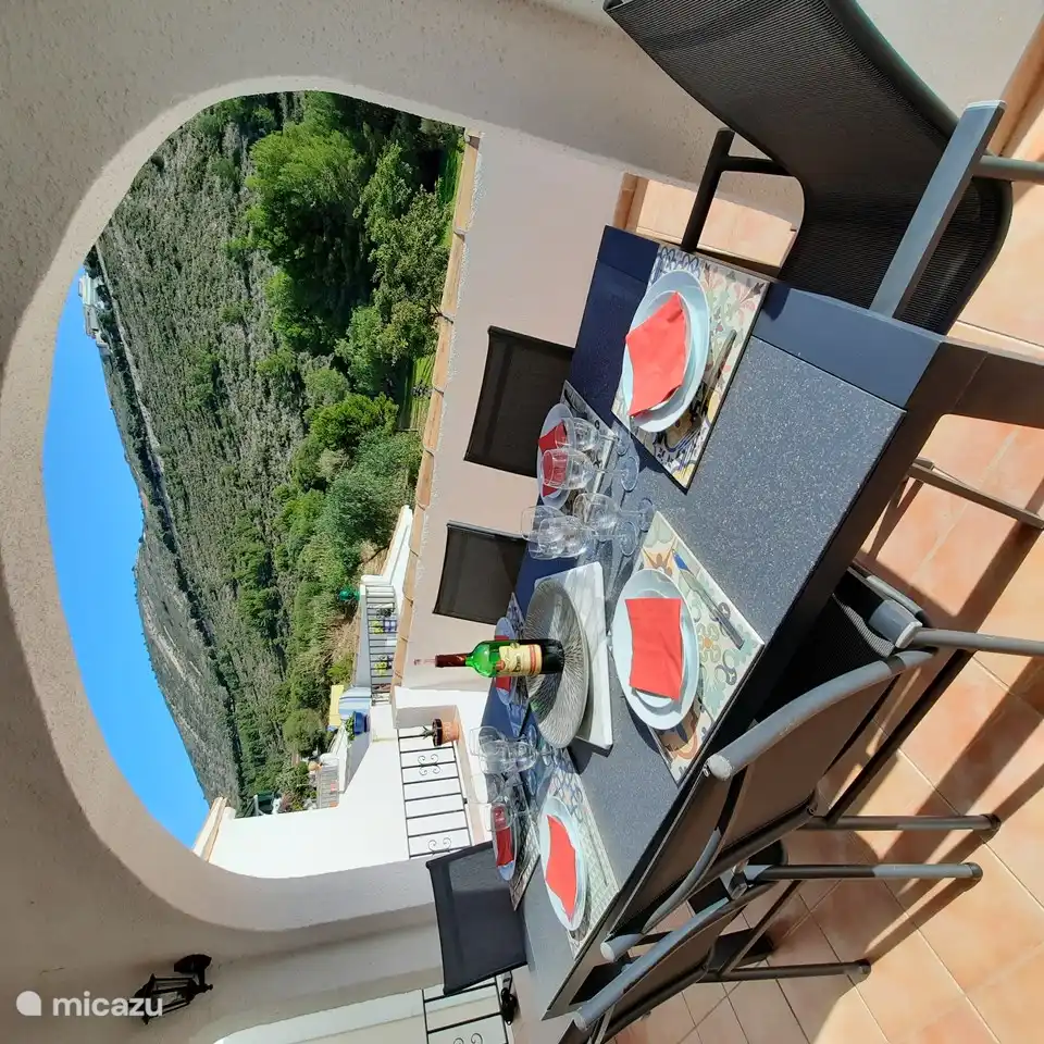 Belle terrasse à côté du salon avec vue sur les montagnes et la mer.