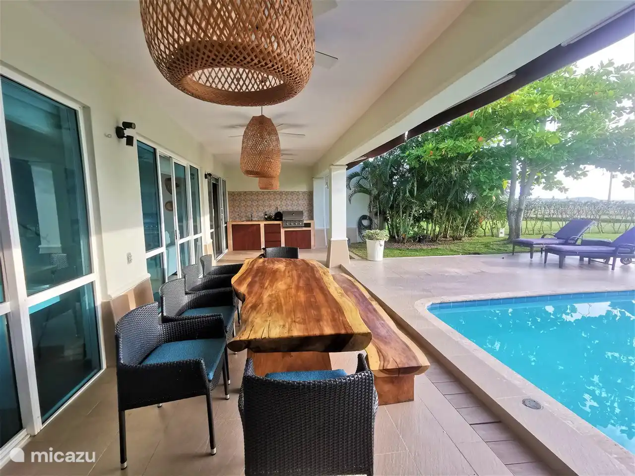 Preciosa terraza cubierta con muebles de diseño y cocina exterior