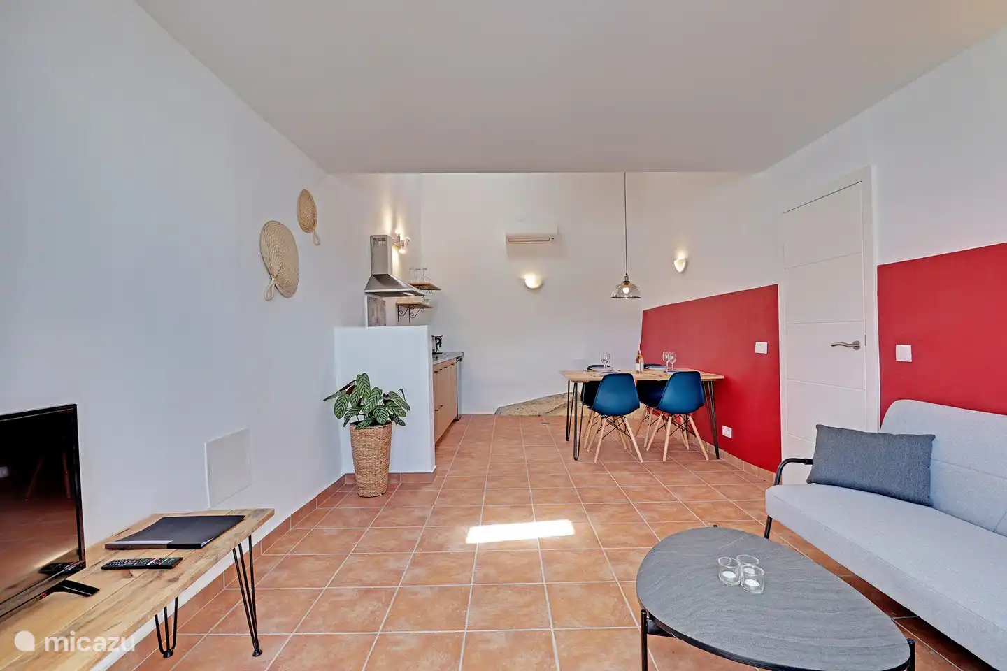 Ein geräumiges Wohnzimmer mit offener Küche. Mit als Extra Feature ein Stück Stein im Wohnzimmer.