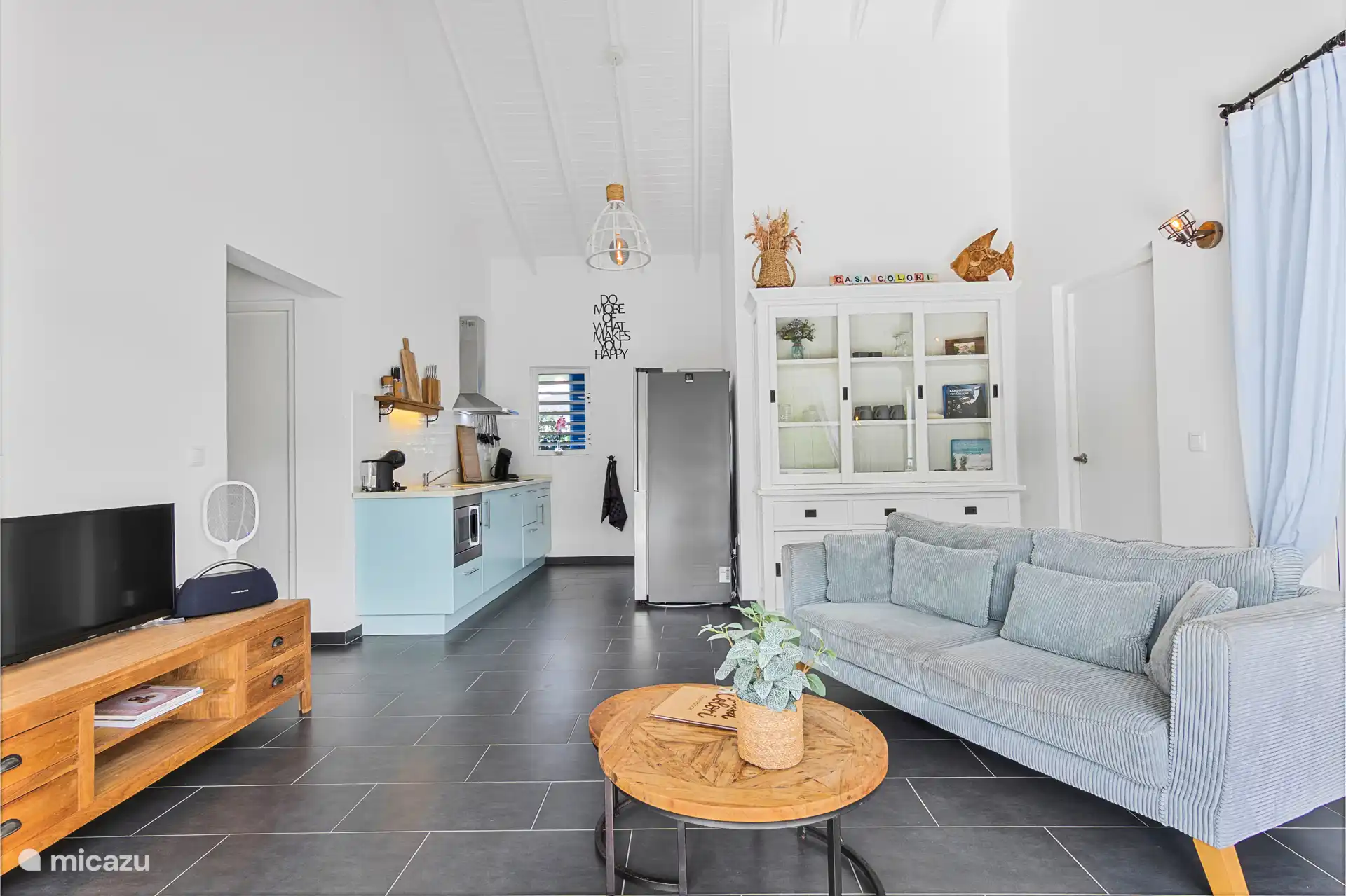 Salón y cocina con techo tropical alto.