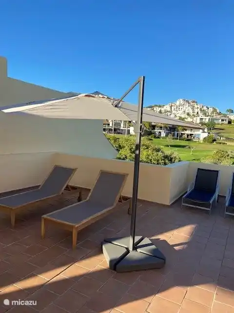 Sonnenbaden auf der Dachterrasse mit dem Clubhaus des Golfclubs Los Arqueros im Hintergrund
