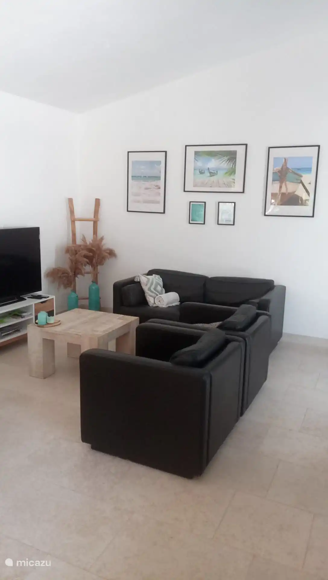 Sala de estar con sofá, 2 sillones, una mesa de comedor y cocina abierta